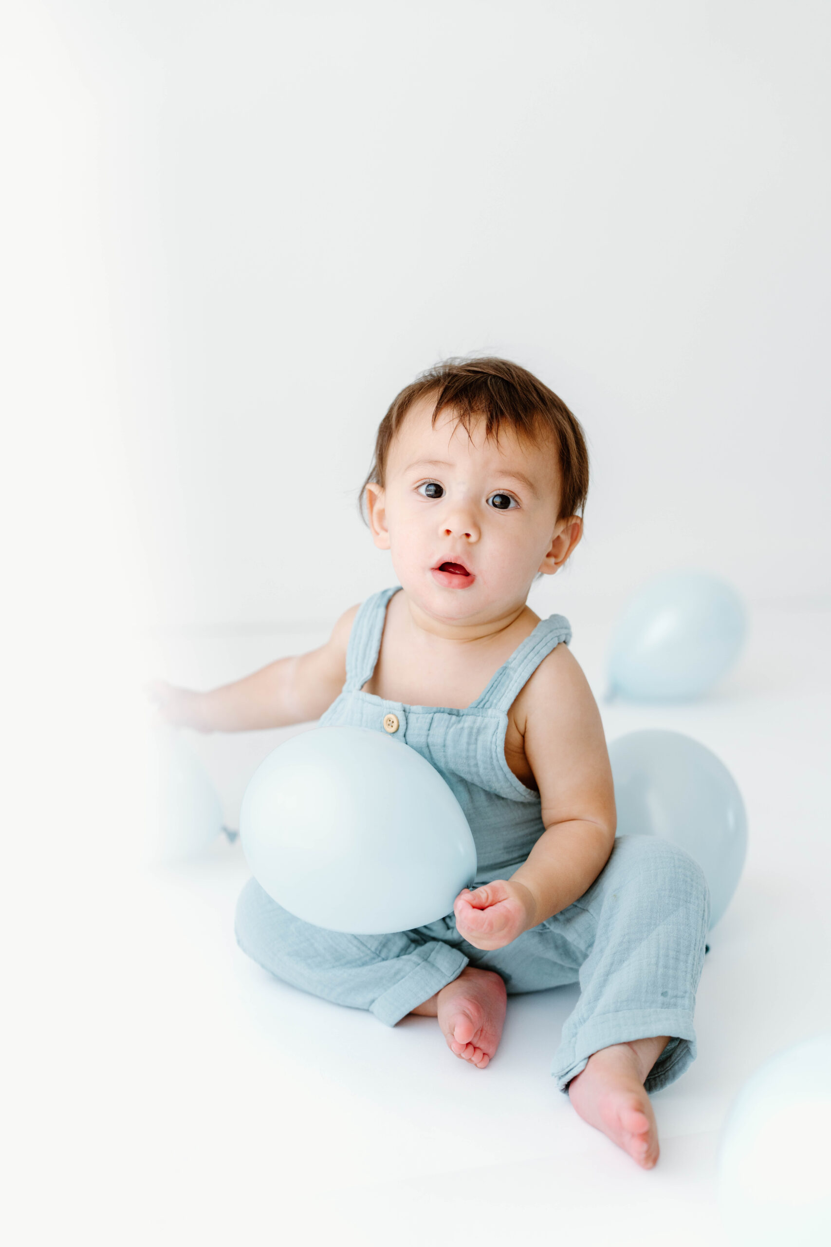 Zachary holds a balloon and looks up at the camera