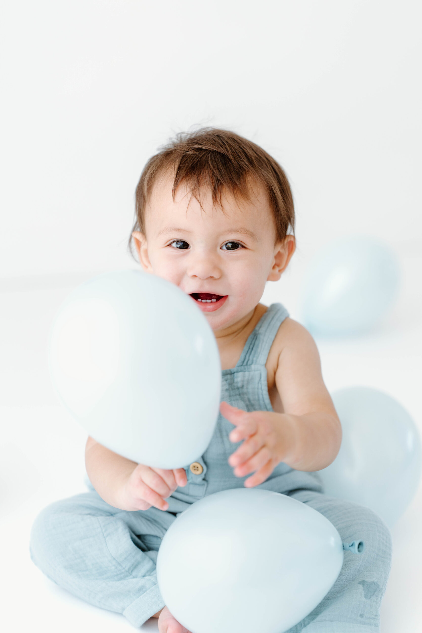 Zachary smiles from behind a blue balloon
