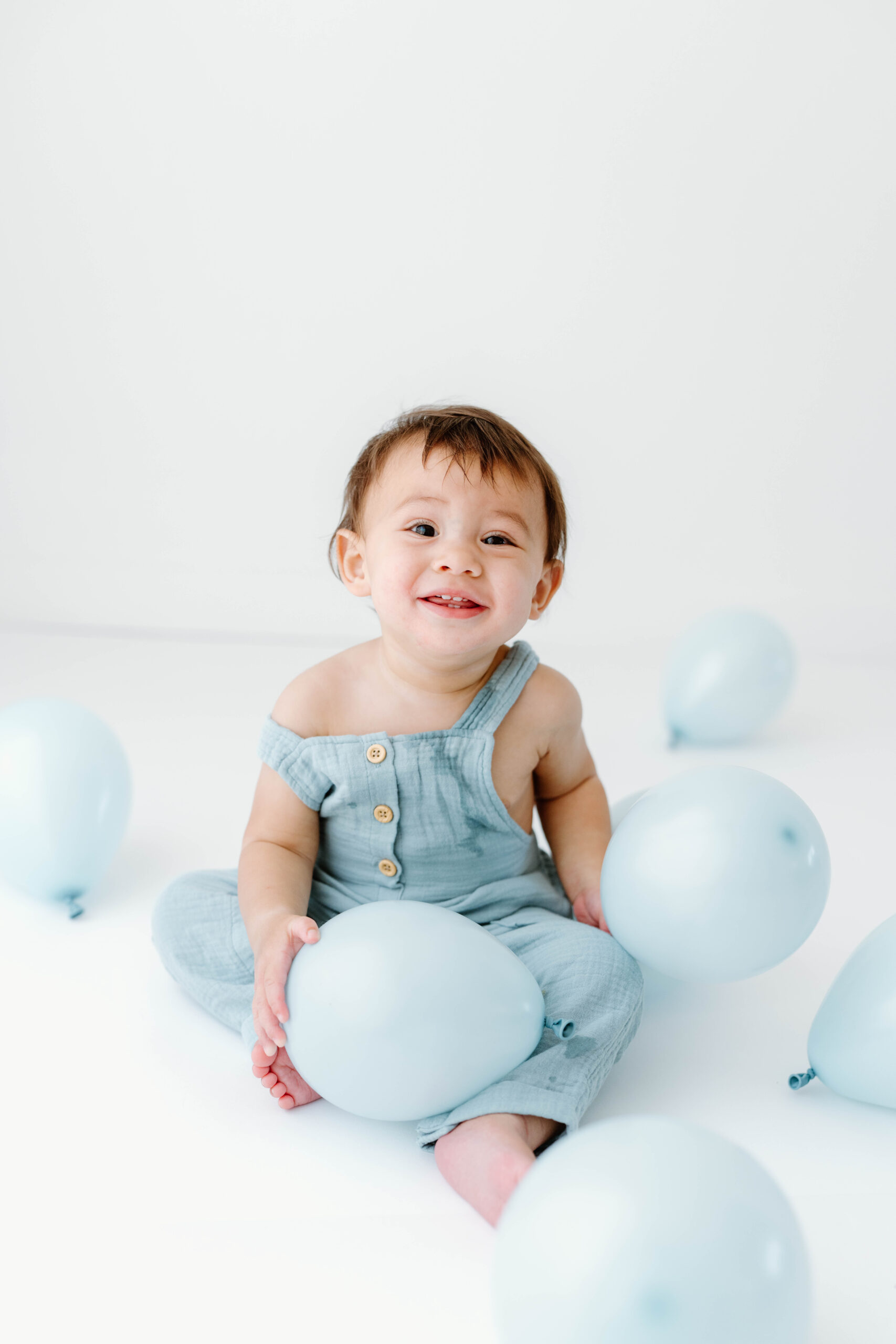 Zachary sits among balloons in the bright studio