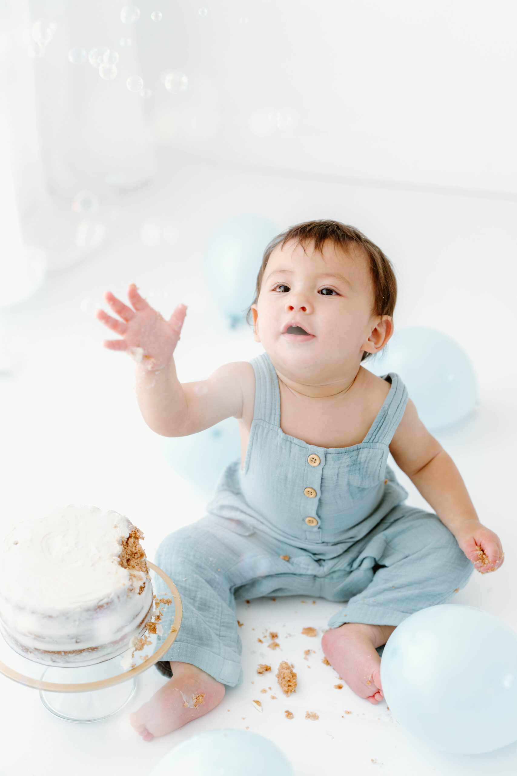 Zachary waves at the bubbles beside his cake