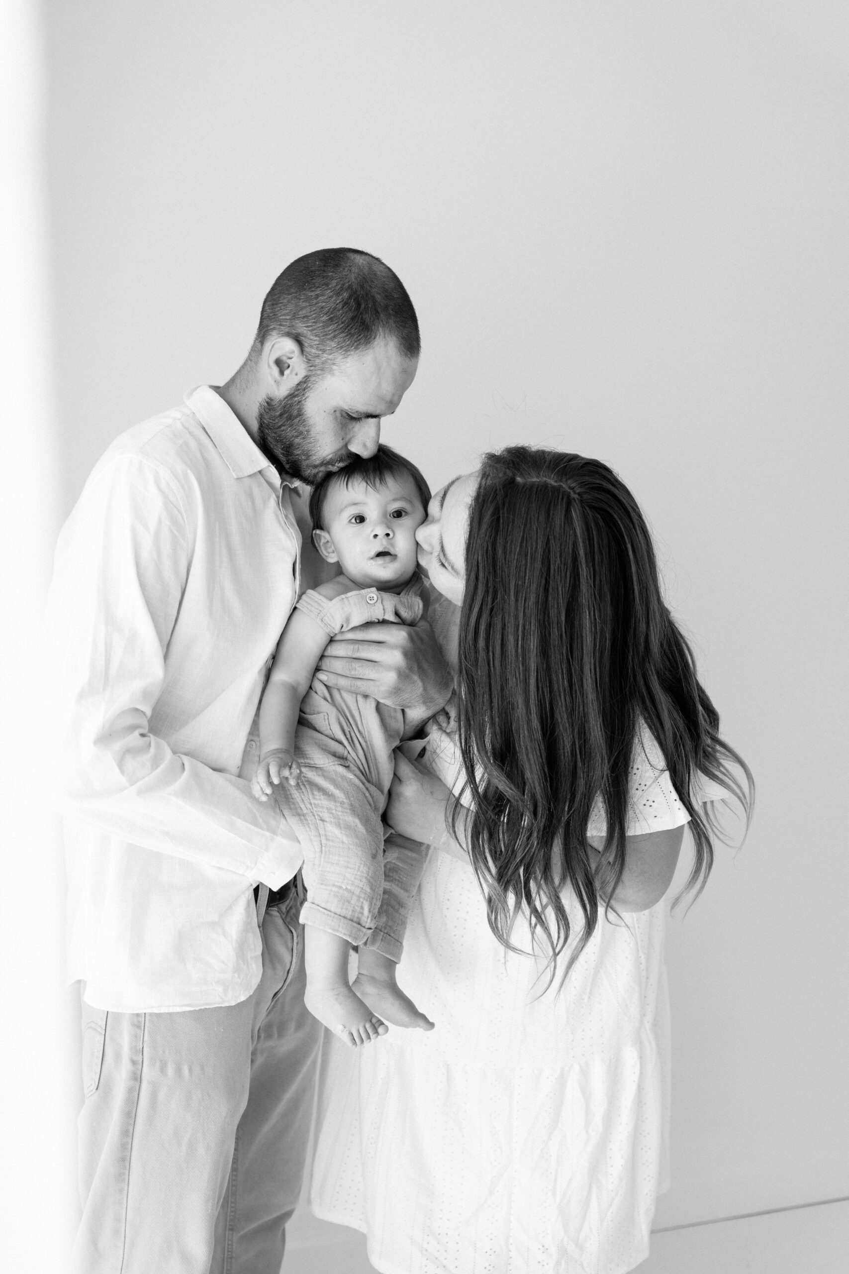 Black-and-white photo of Zachary's parents kissing his cheeks