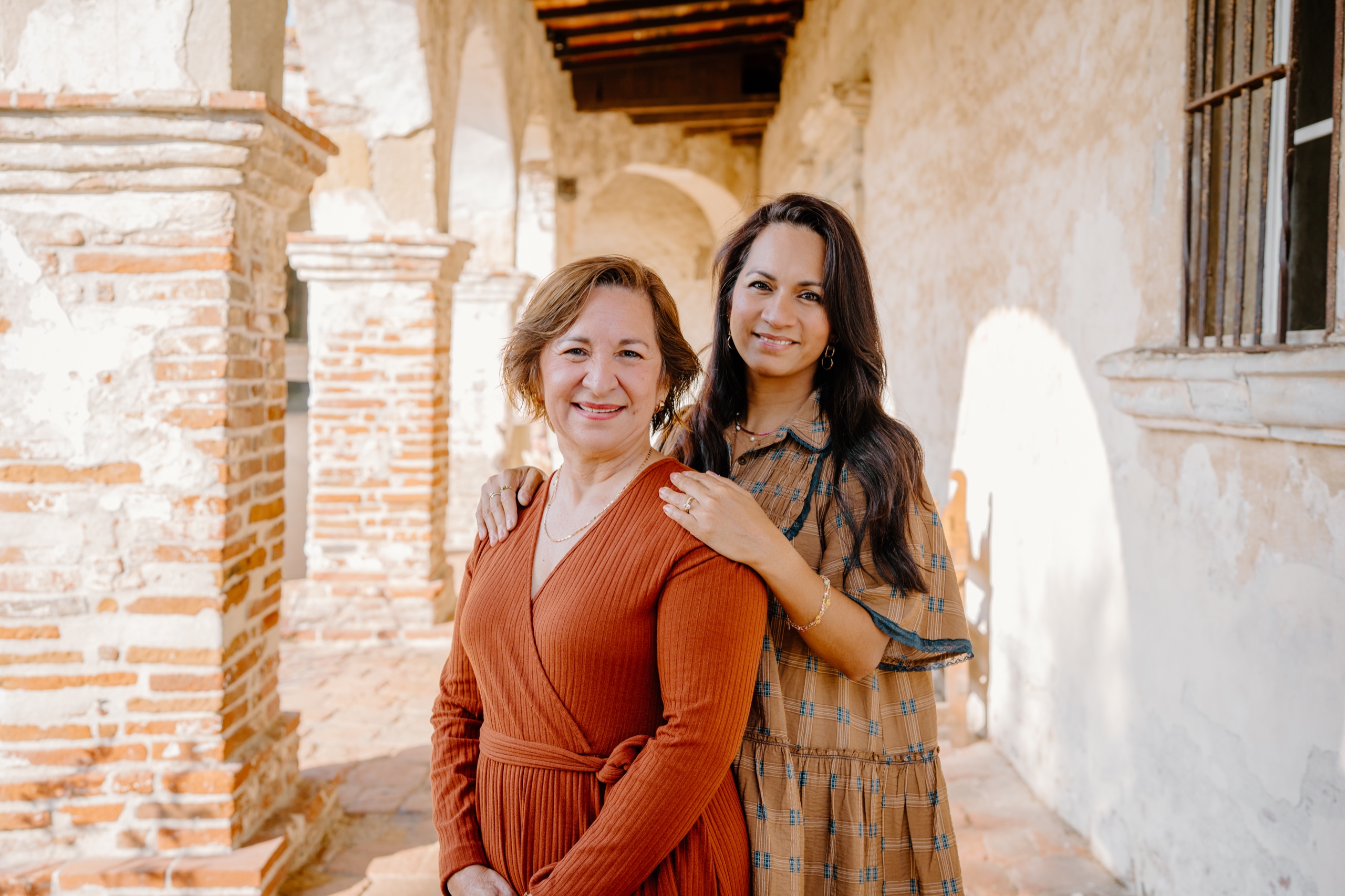 Two women arm in arm smiling in the Mission’s arcade