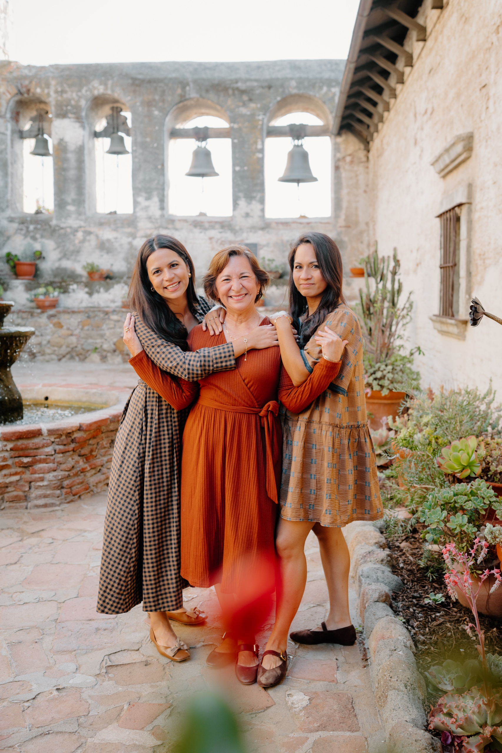 Three women laughing together in a Mission courtyard