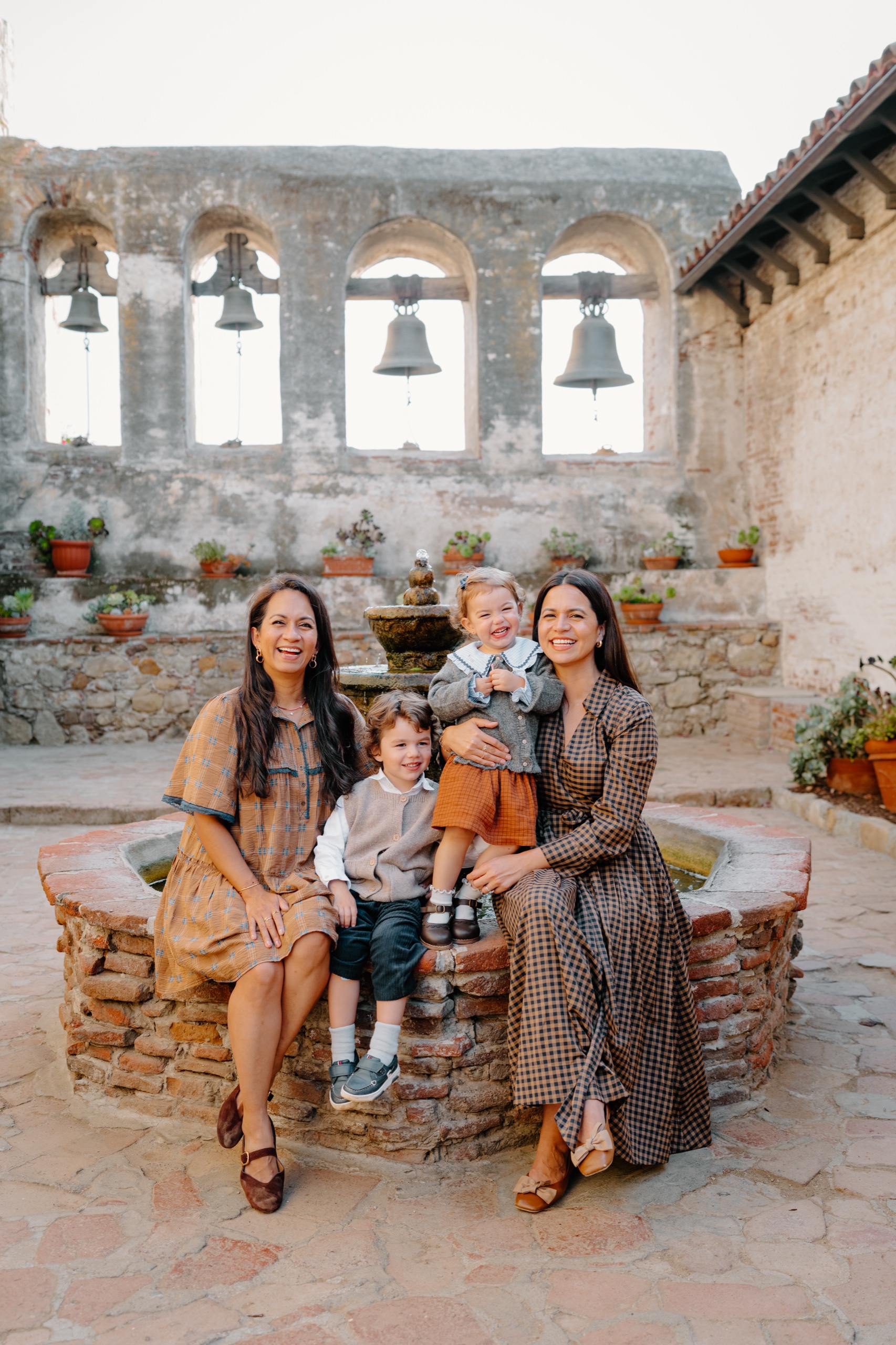 Two women and two children sitting on the edge of the Mission fountain