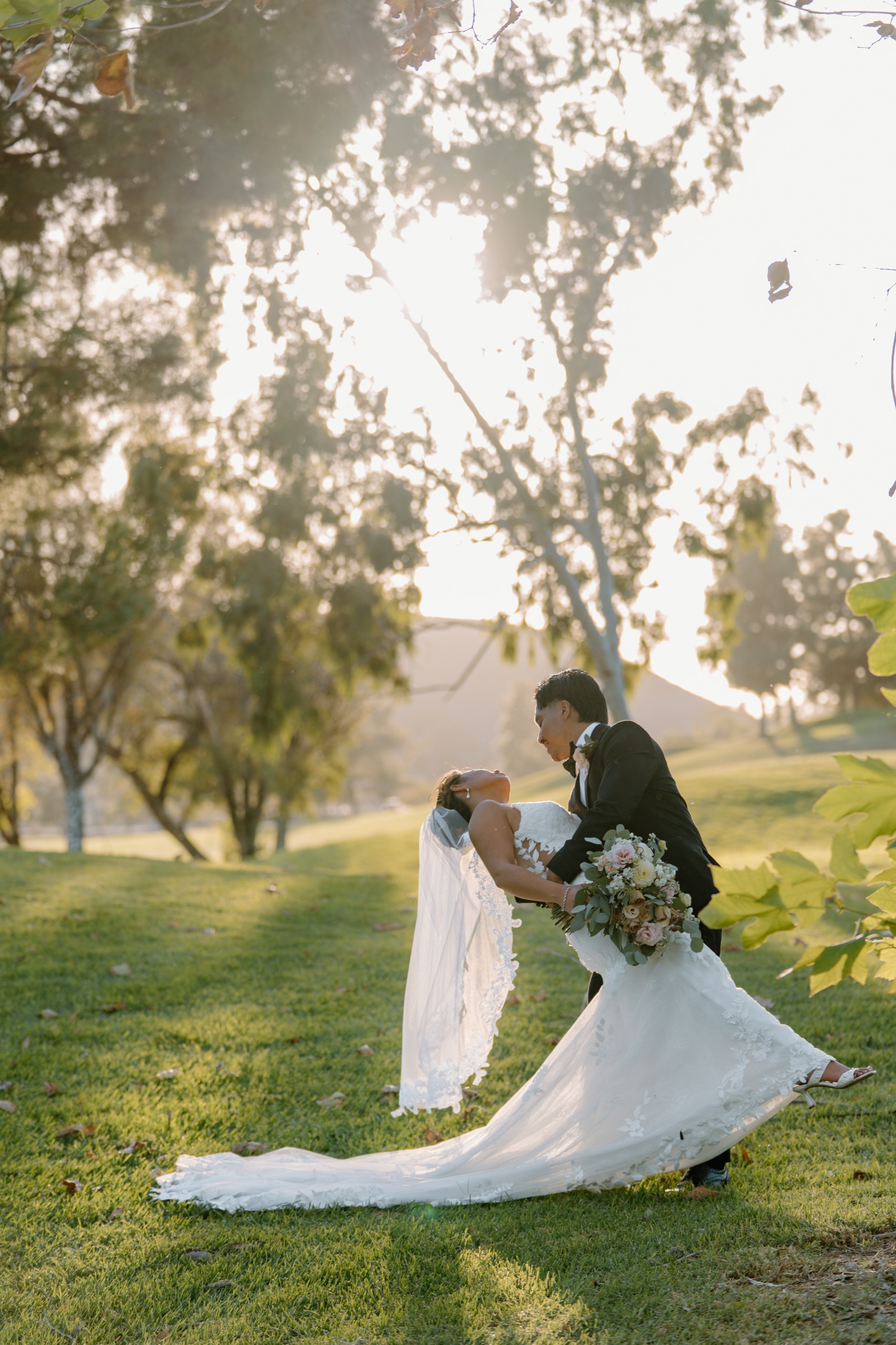 Groom dipping his bride on the lawn in golden hour light at Mountain Meadows Golf Course