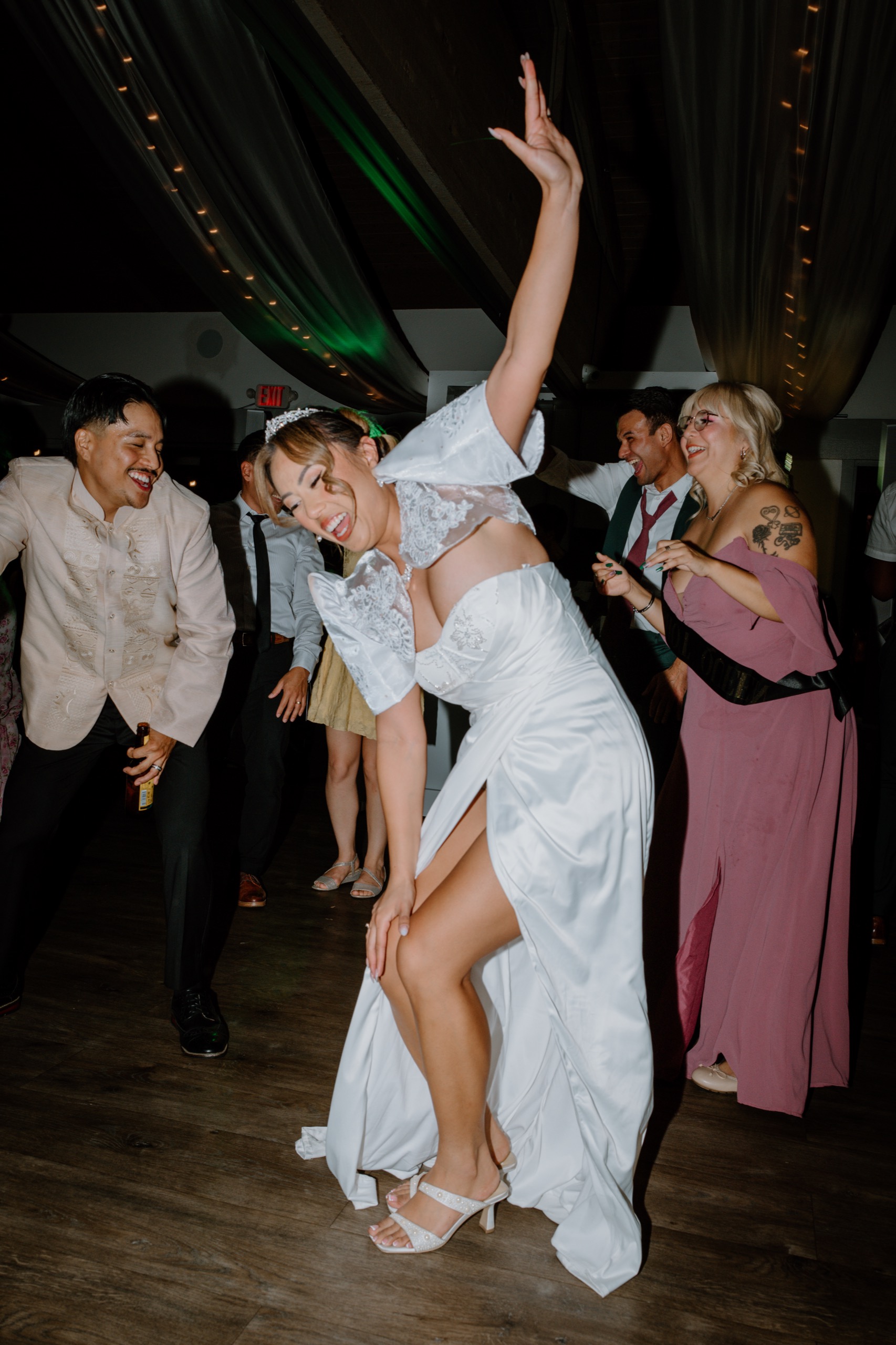 Bride dancing with her arm raised on a crowded dance floor